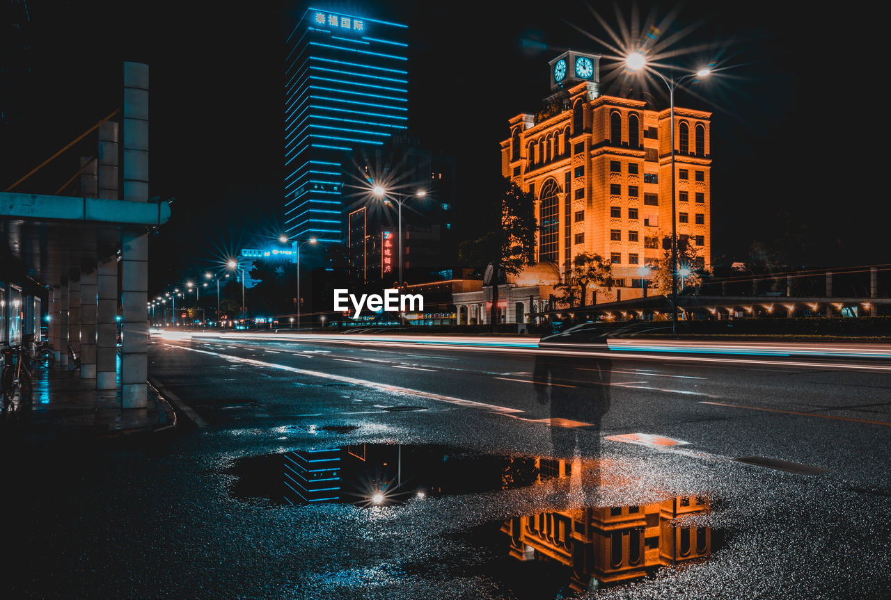 ILLUMINATED CITY STREET AGAINST SKY AT NIGHT