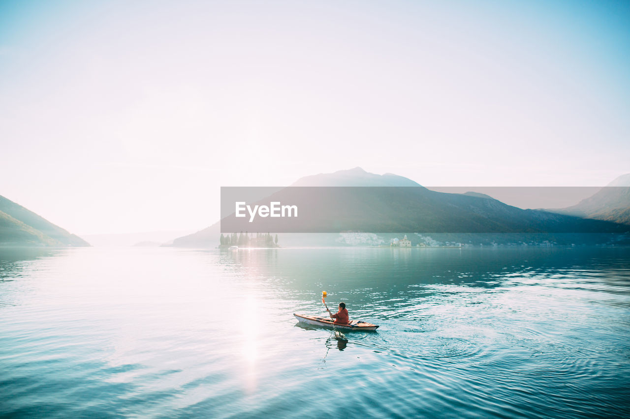 MAN ON LAKE AGAINST SKY