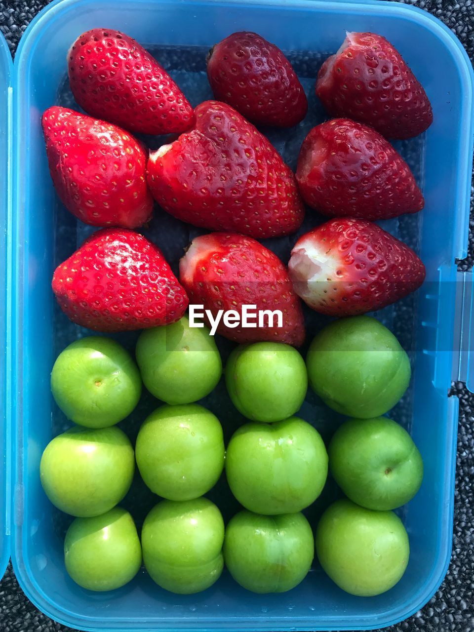 High angle view of strawberries and greengage in container