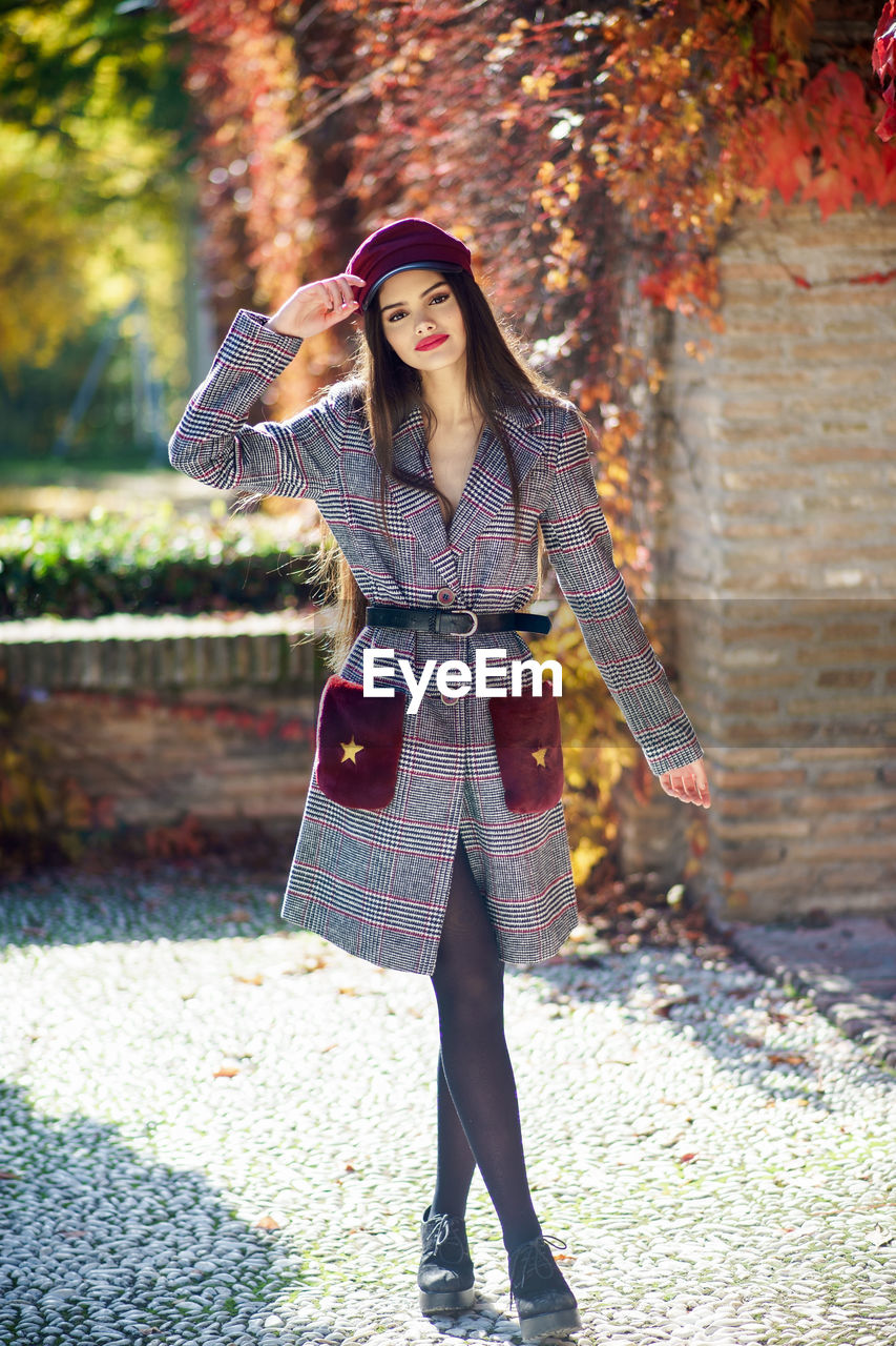 Portrait of beautiful model standing against autumn plants