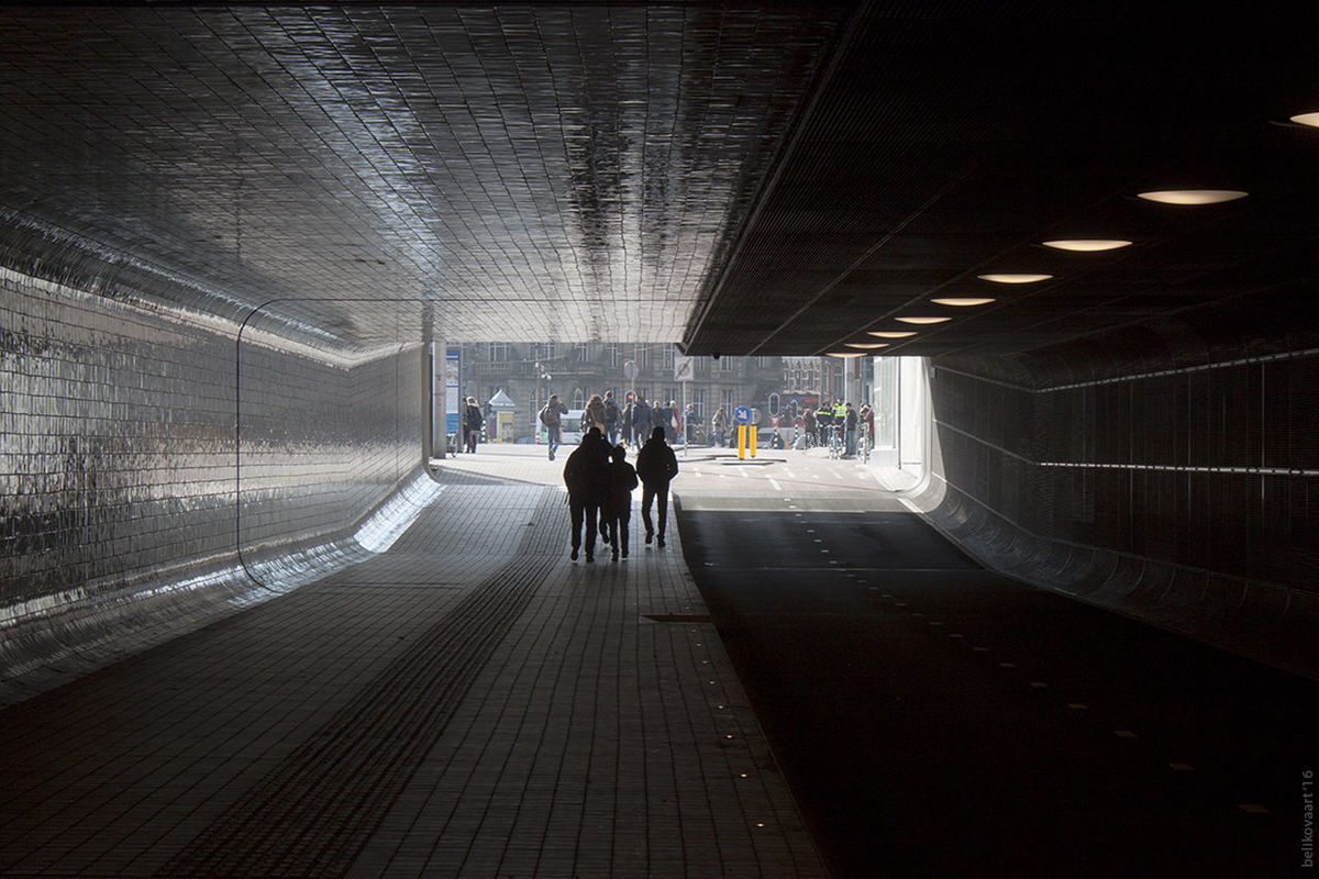 REAR VIEW OF WOMAN WALKING IN TUNNEL