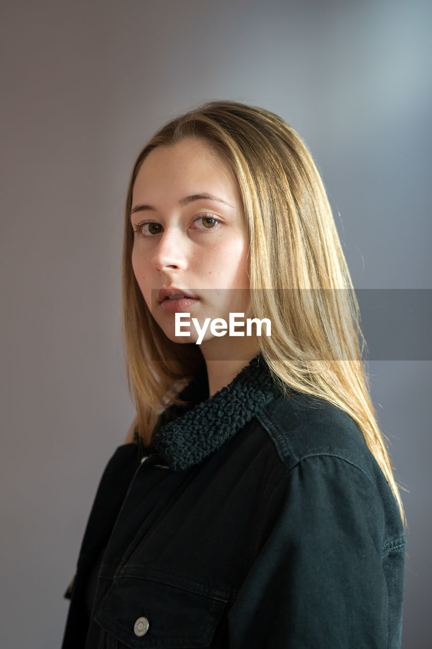 Portrait of a beautiful young woman against grey background