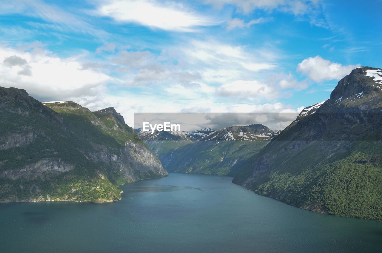 Scenic view of river amidst mountains against cloudy sky