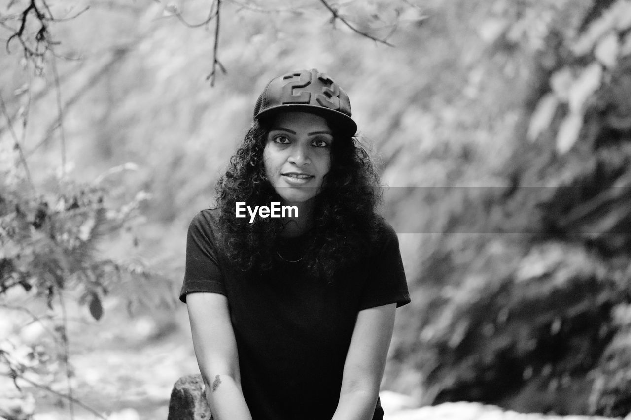 Portrait of smiling woman standing against trees in nature