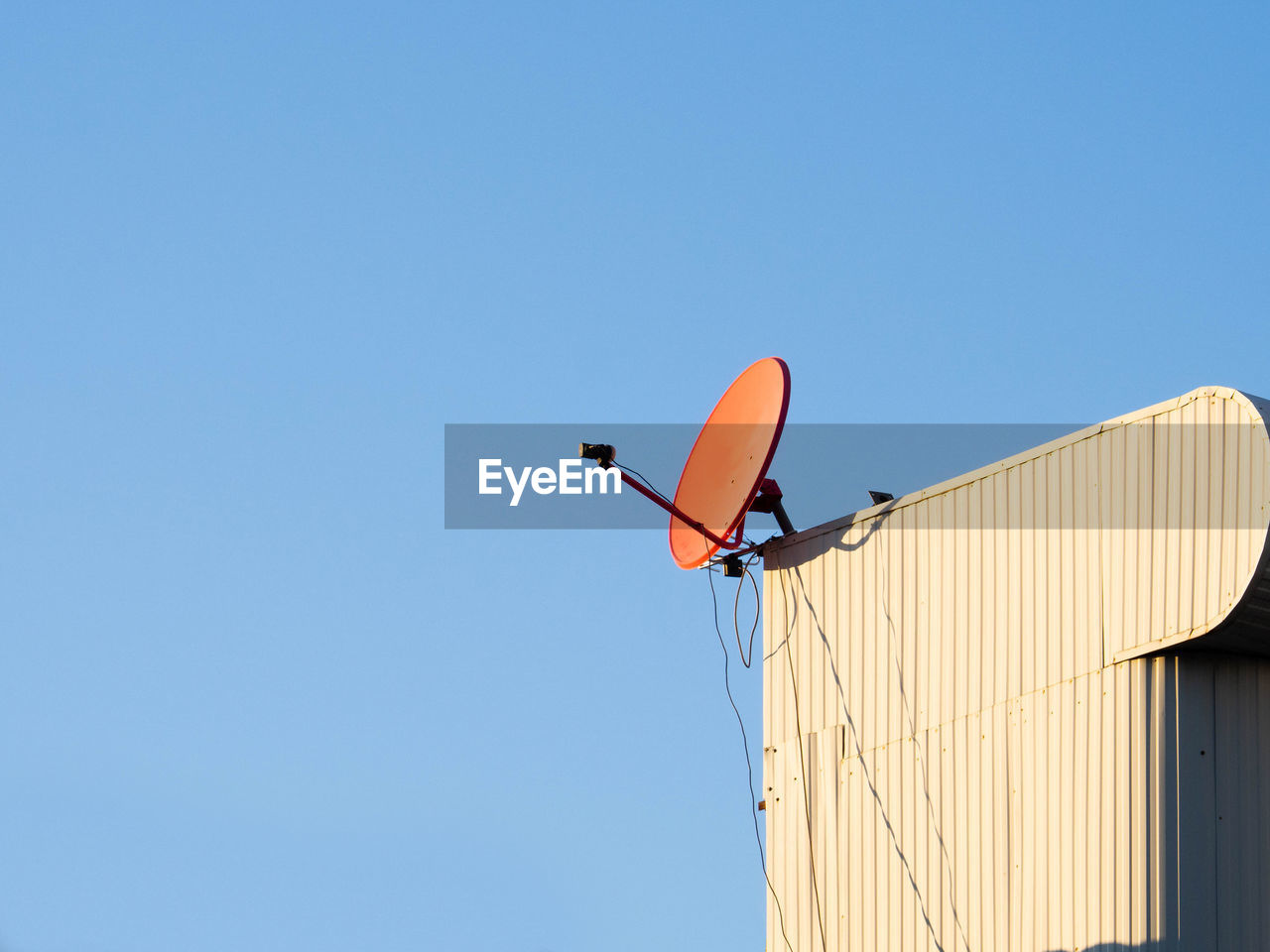 Red satellite dish hangking on roof top of building