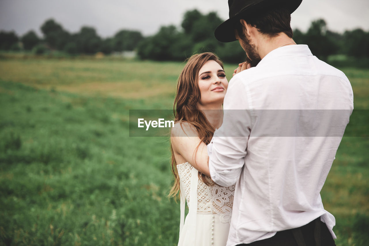 Young couple holding hands while standing on field