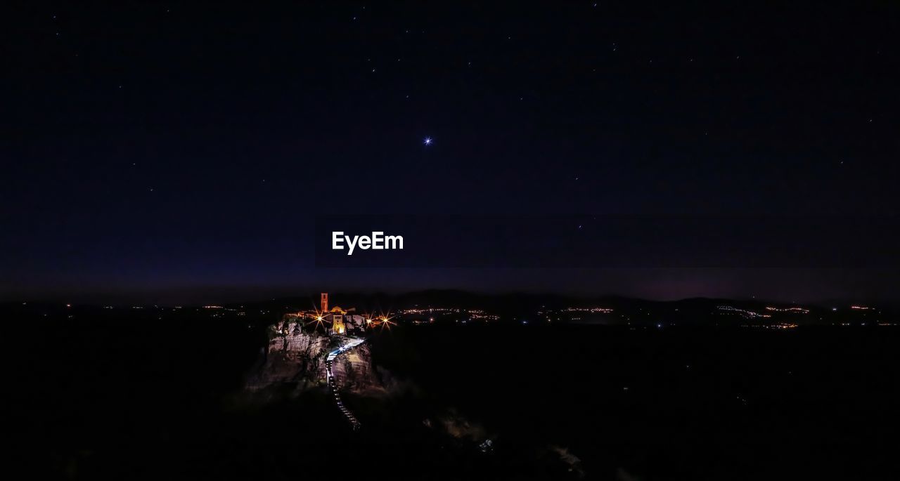 AERIAL VIEW OF ILLUMINATED CITY AGAINST SKY