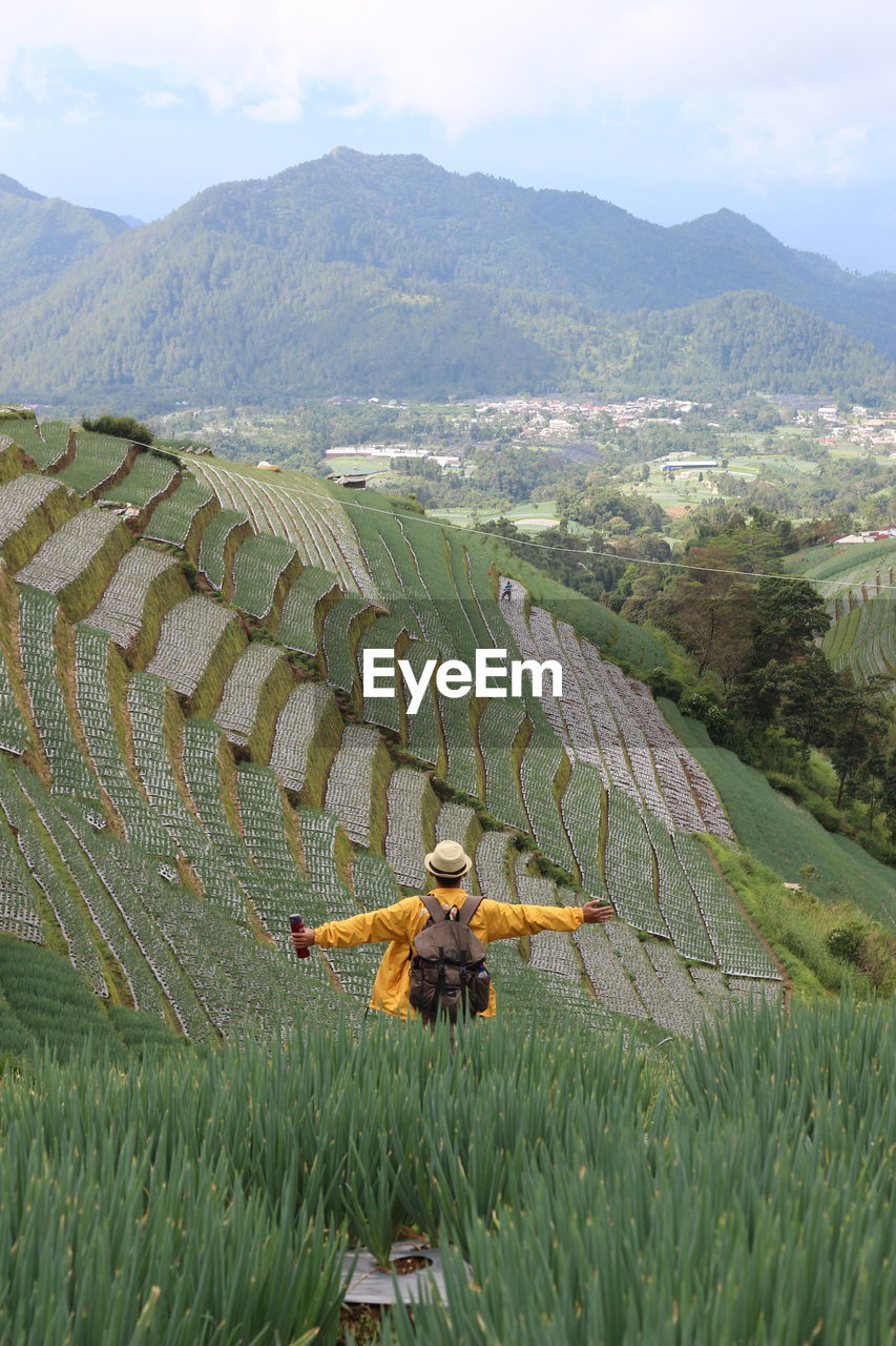 Rear view of woman walking on field against sky