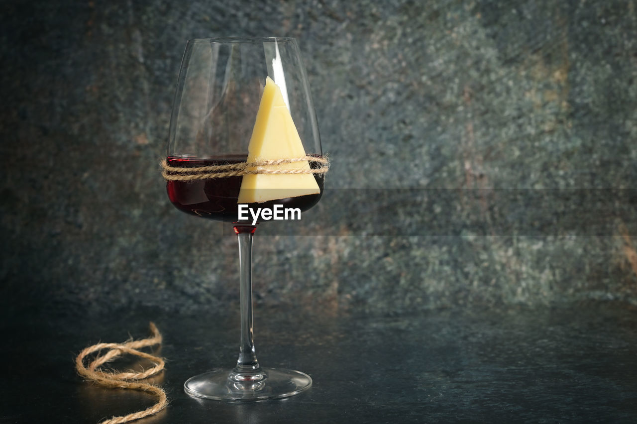 Dry glass of red wine and cheese on stone background