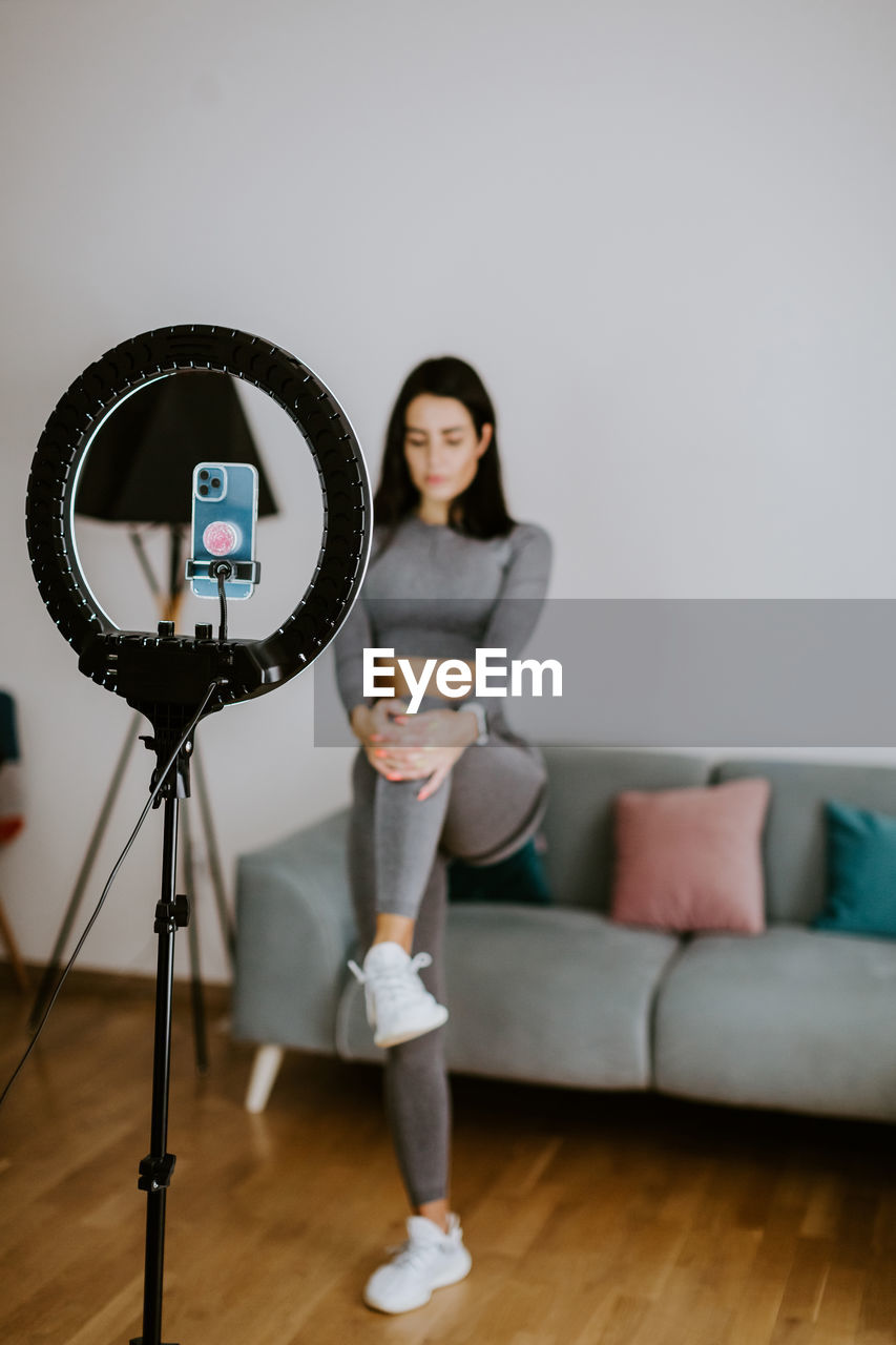 PORTRAIT OF YOUNG WOMAN PHOTOGRAPHING AT HOME