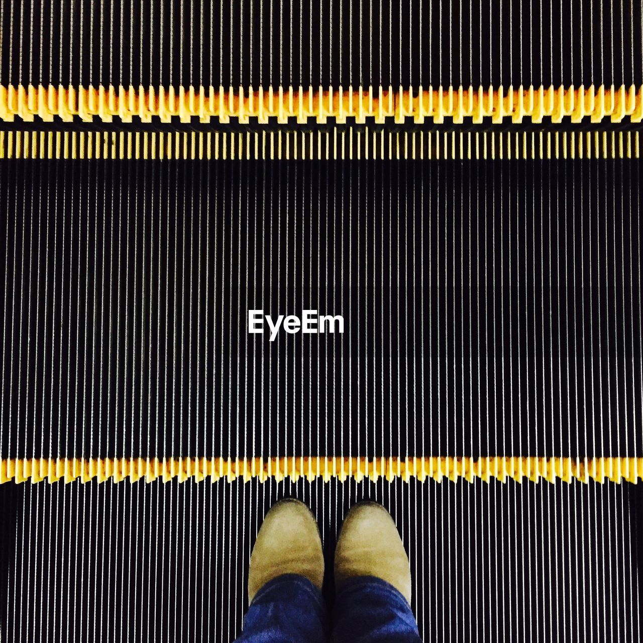 Low section of person standing on escalator