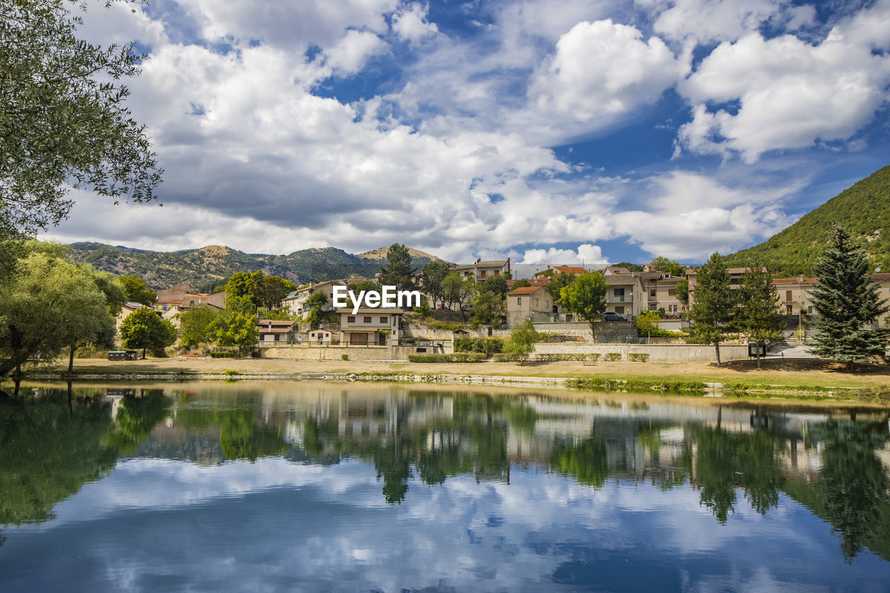 scenic view of lake by trees against cloudy sky