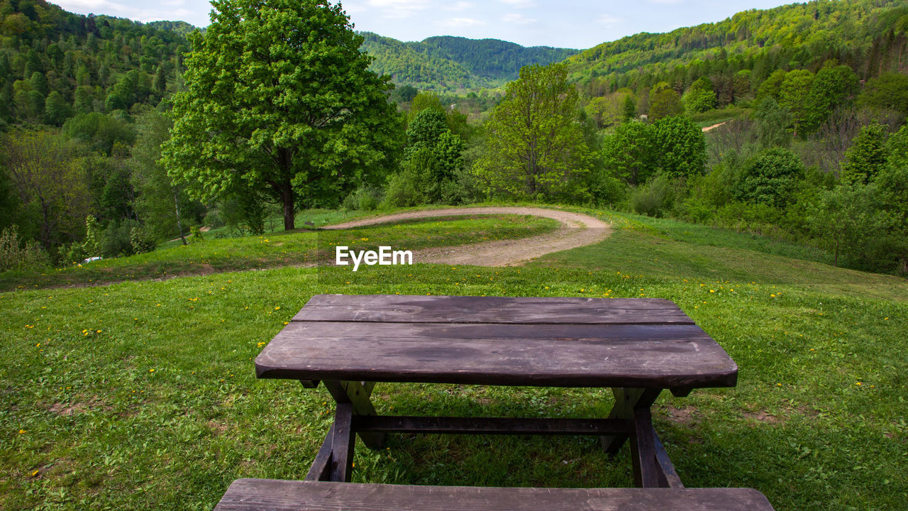 EMPTY BENCH IN PARK BY GREEN MOUNTAINS