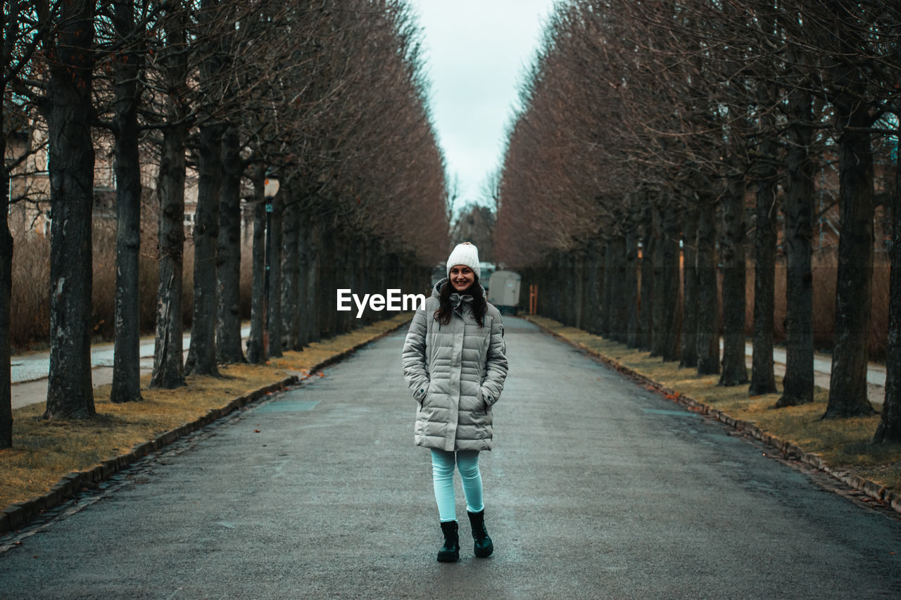 Rear view of man walking on road amidst trees