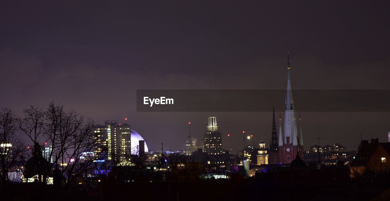 LOW ANGLE VIEW OF ILLUMINATED CITY AGAINST SKY