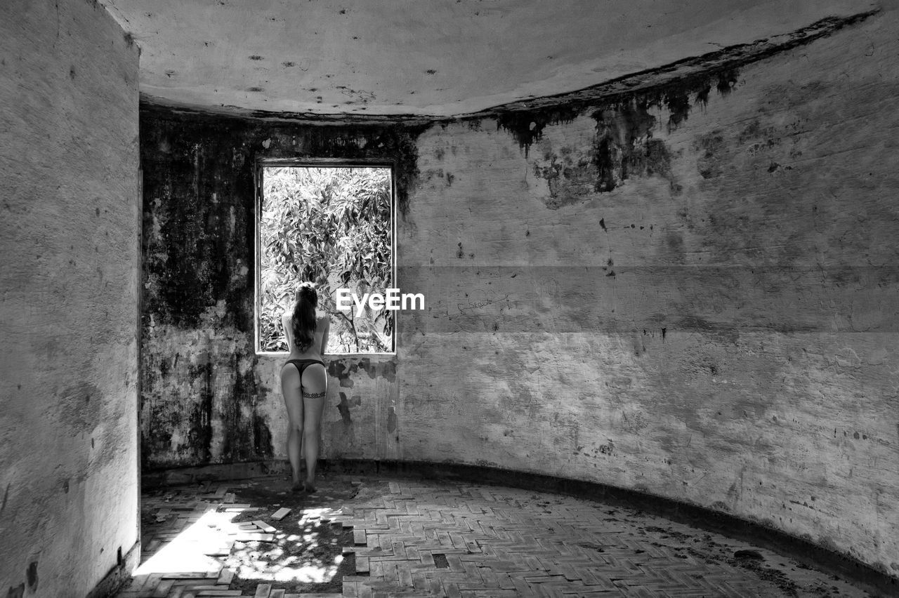 Rear view of young woman standing in abandoned building