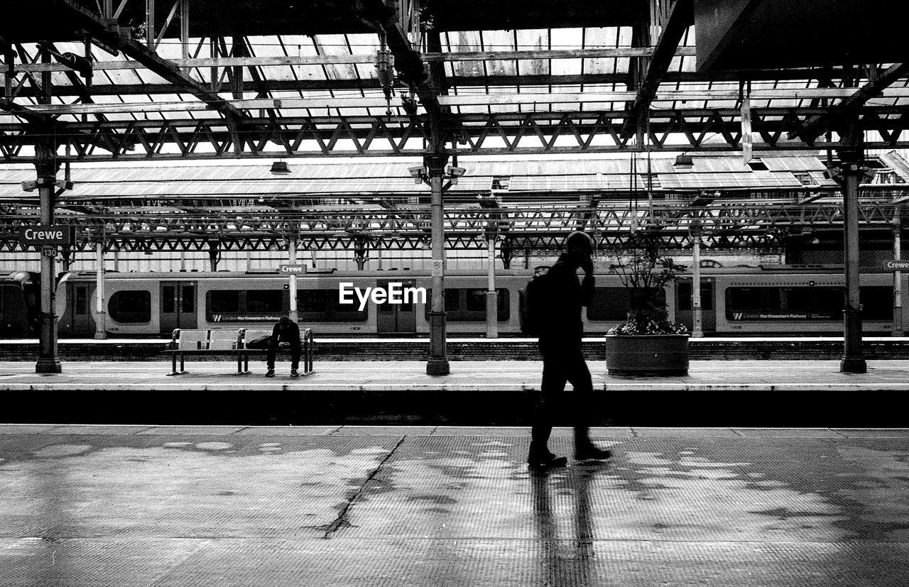 FULL LENGTH OF MAN WALKING ON RAILROAD STATION PLATFORM