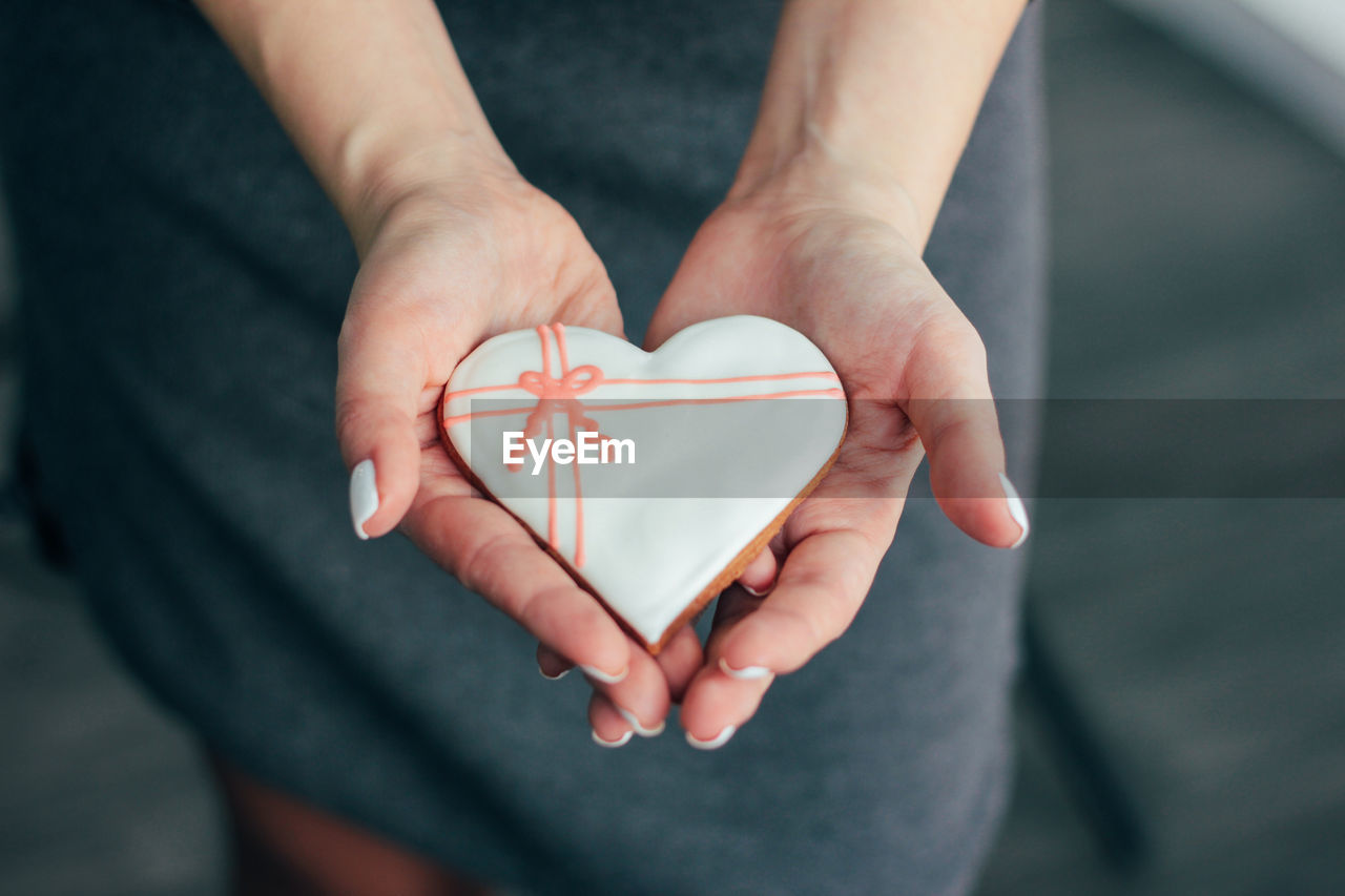 Midsection of woman holding heart shape gingerbread cookie