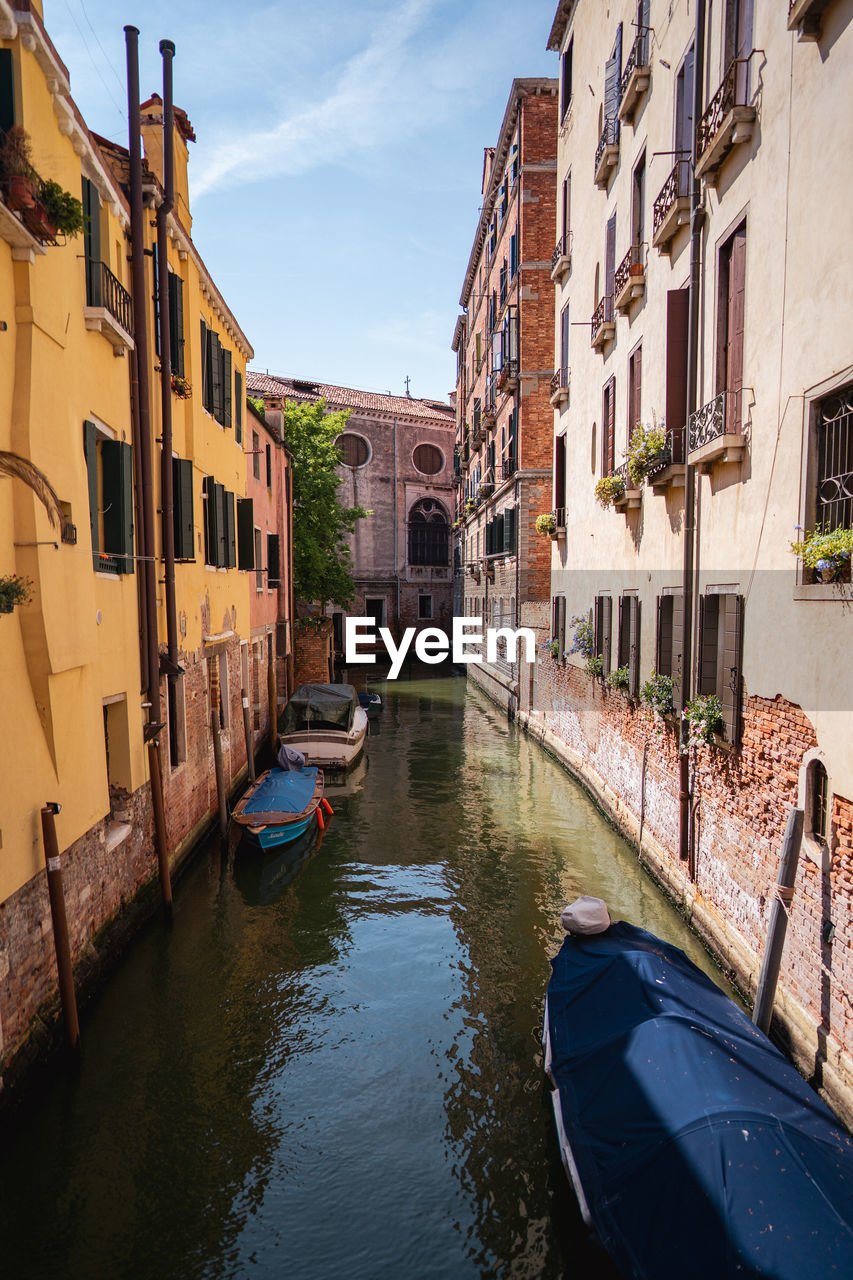 boats in canal amidst buildings