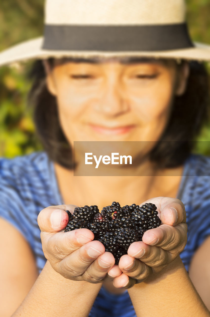 Happy mid adult woman holding mulberries