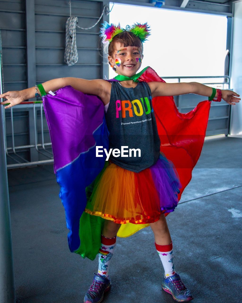 Portrait of cheerful girl wearing colorful costume while standing against wall