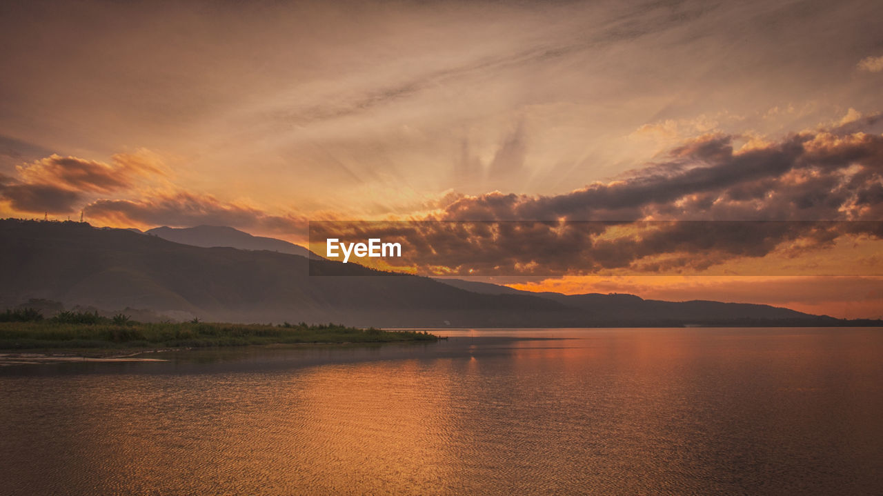 SCENIC VIEW OF LAKE AND MOUNTAINS AGAINST SKY DURING SUNSET