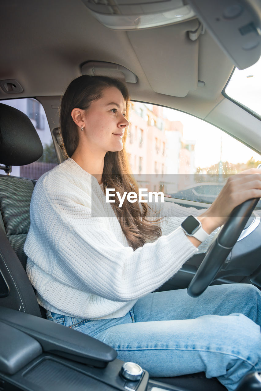 portrait of young woman using mobile phone while sitting in car