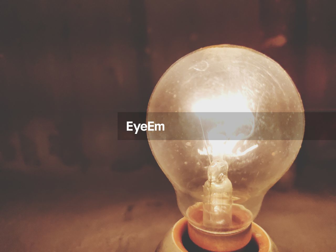 CLOSE-UP OF ILLUMINATED LIGHT BULB ON THE WALL