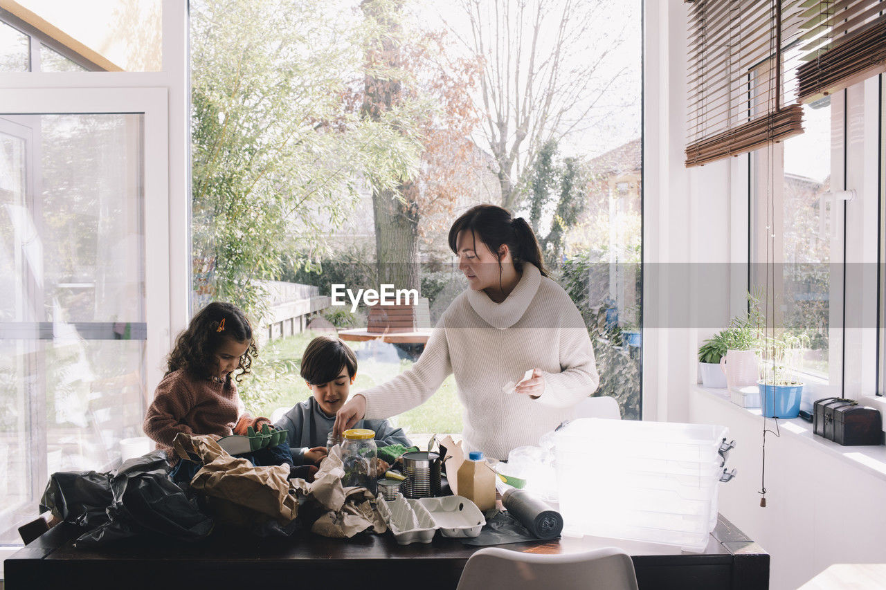 Woman separating waste with son and daughter at home