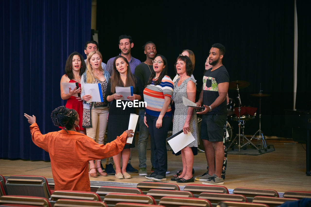 Teacher directing choir on stage in language school