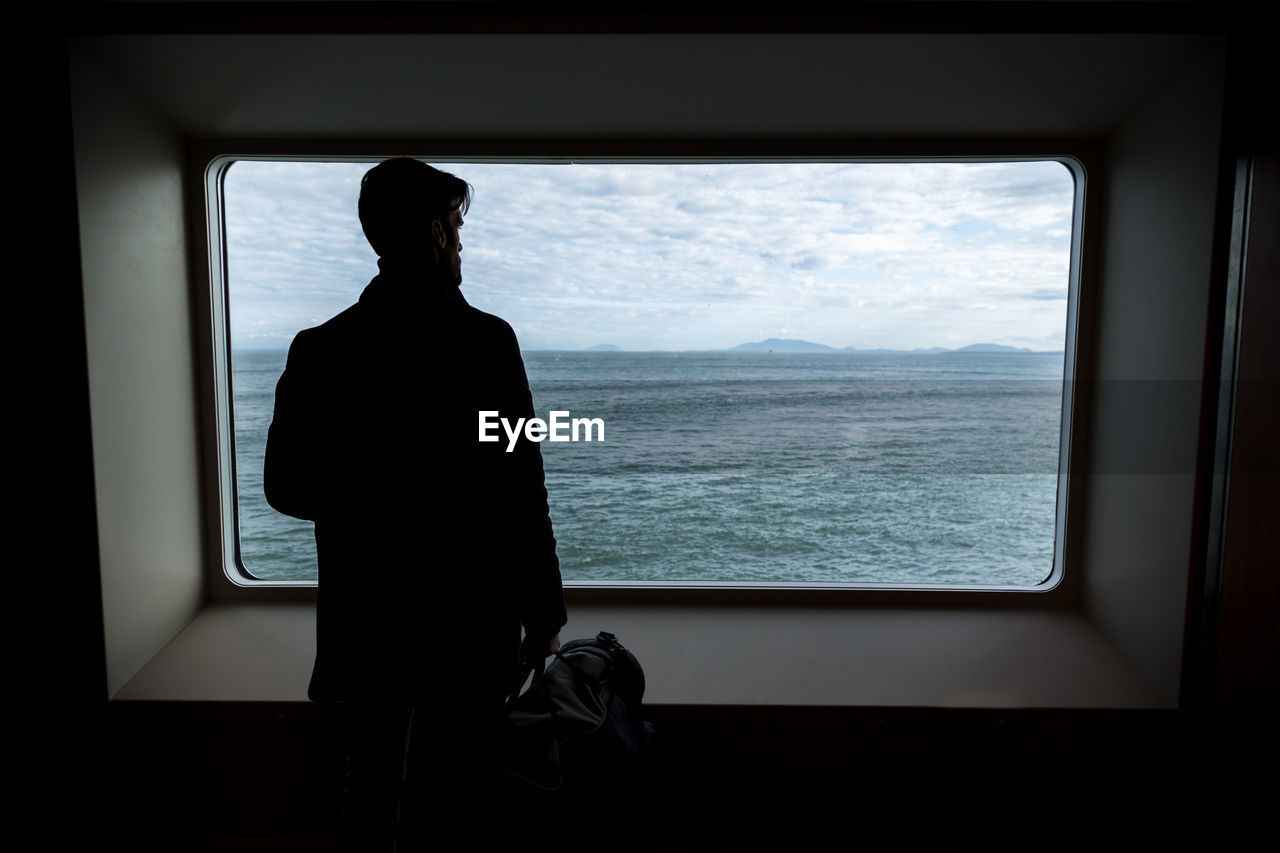 Man looking through window at sea