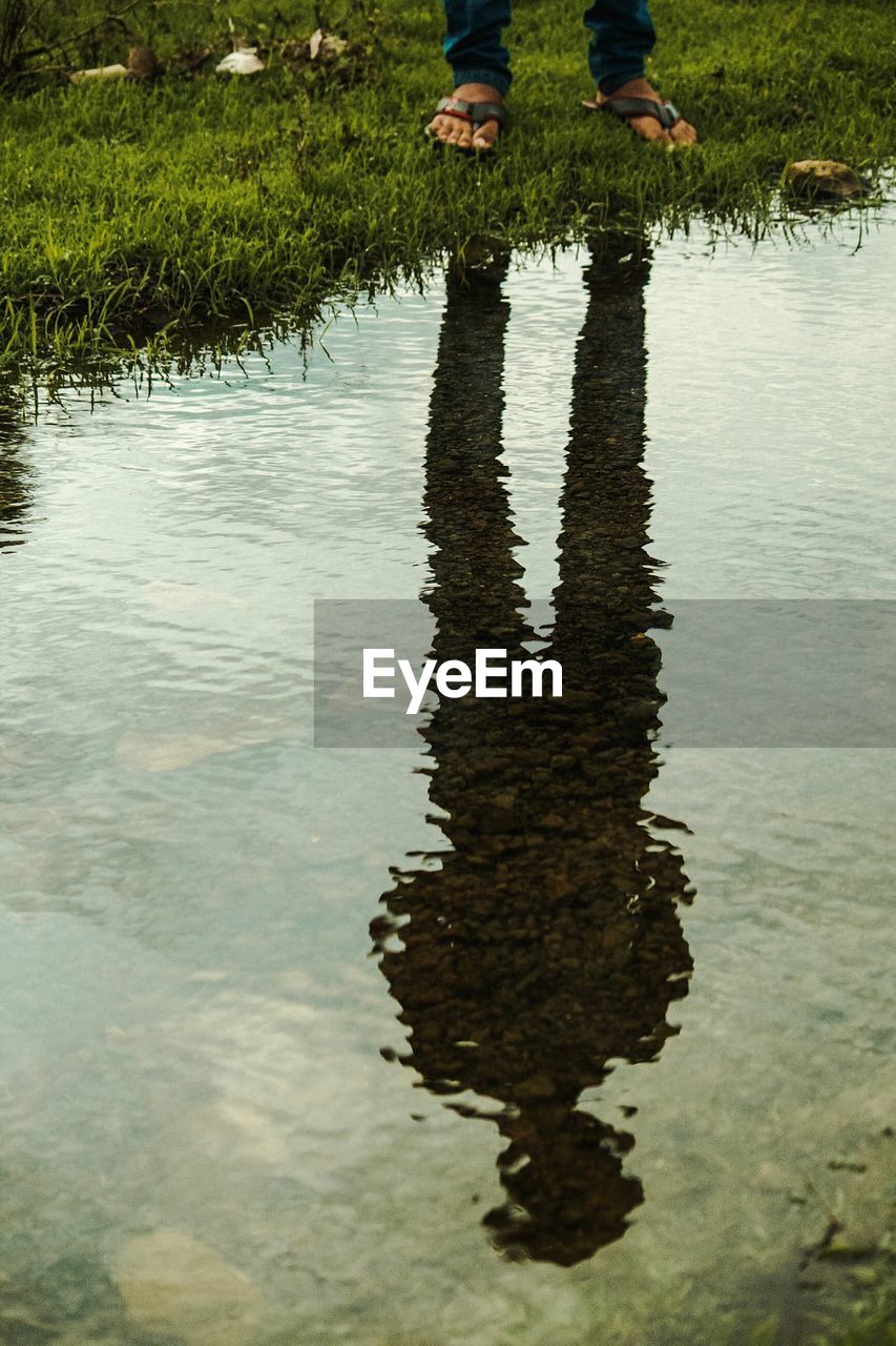 LOW SECTION OF PERSON STANDING AT LAKE