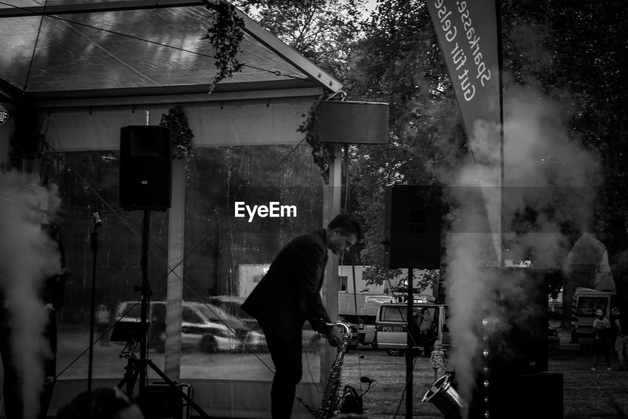 MAN STANDING ON STREET BY TREES IN CITY