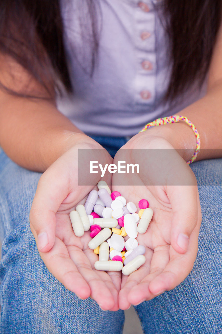 Midsection of woman holding medicines in cupped hands