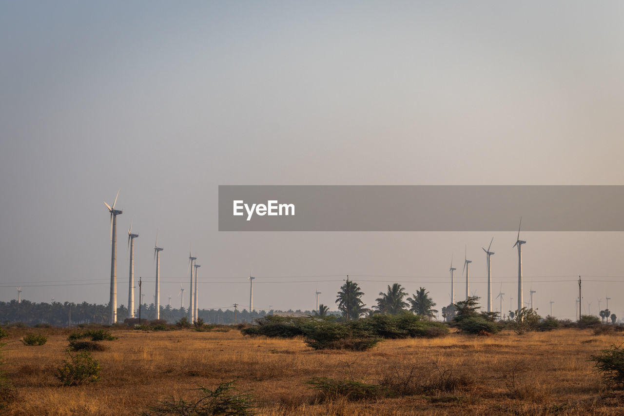 WINDMILLS ON FIELD AGAINST SKY