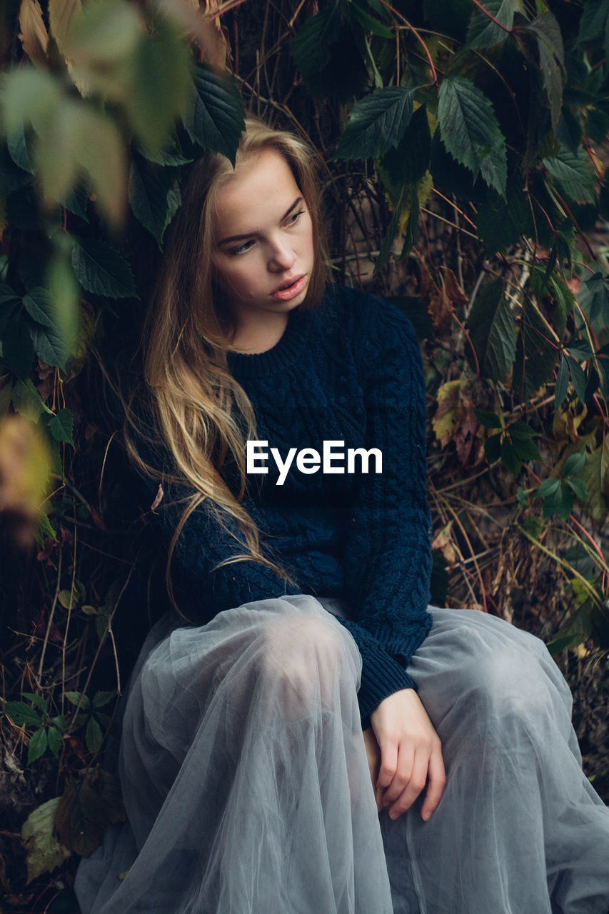 High angle view of thoughtful young woman looking away while sitting by plants