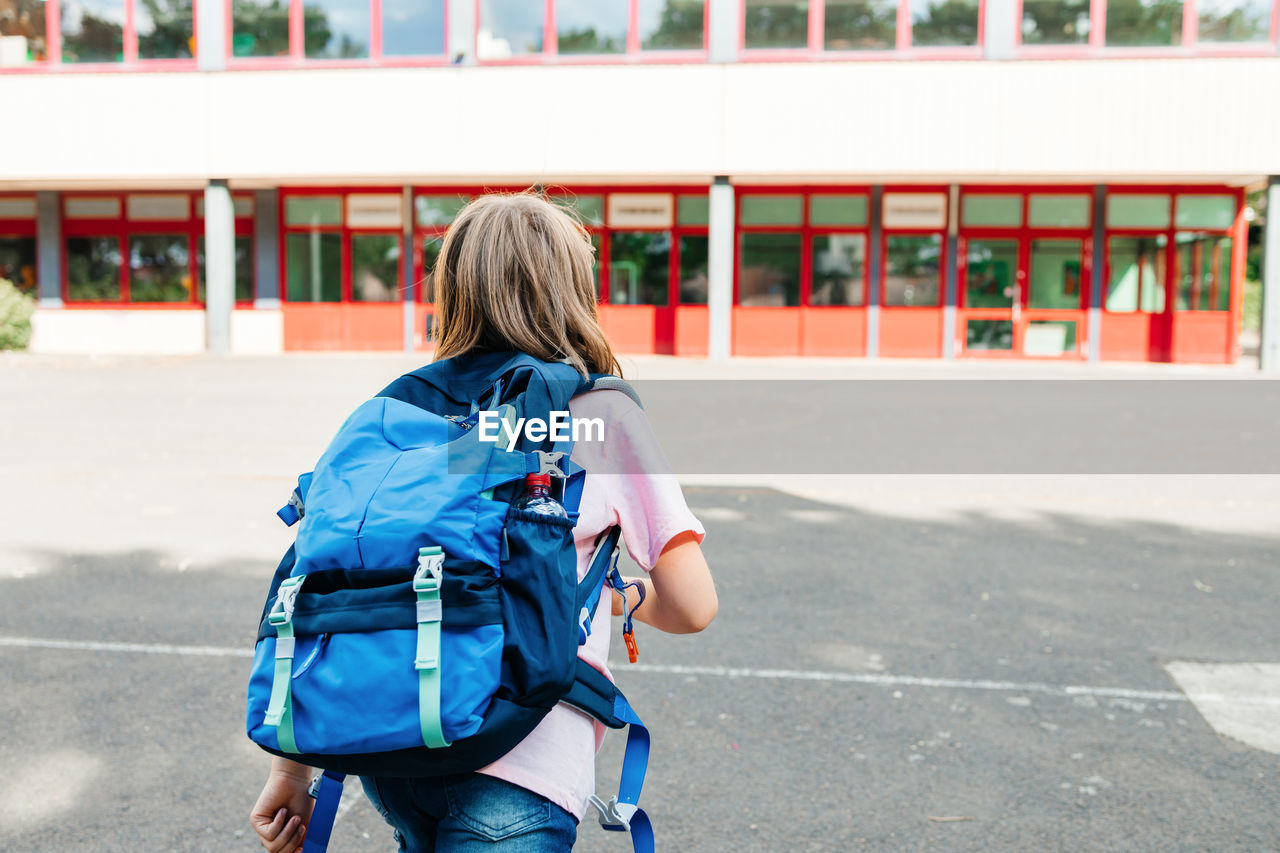 A schoolgirl girl with a school backpack on her back runs to school. 