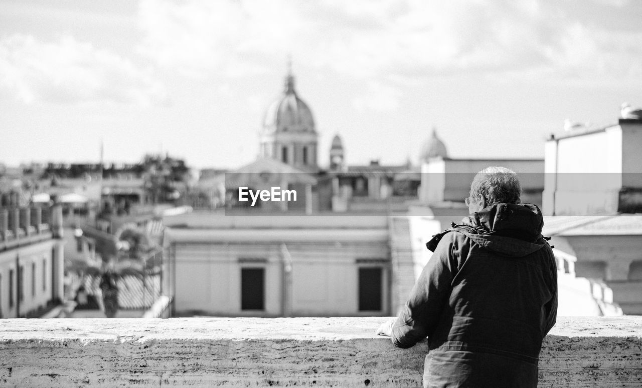 Rear view of man standing on terrace against historic church in city