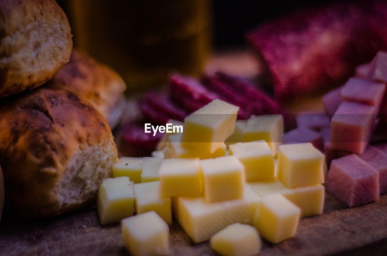 High angle view of chopped cheese and salami by bread on table