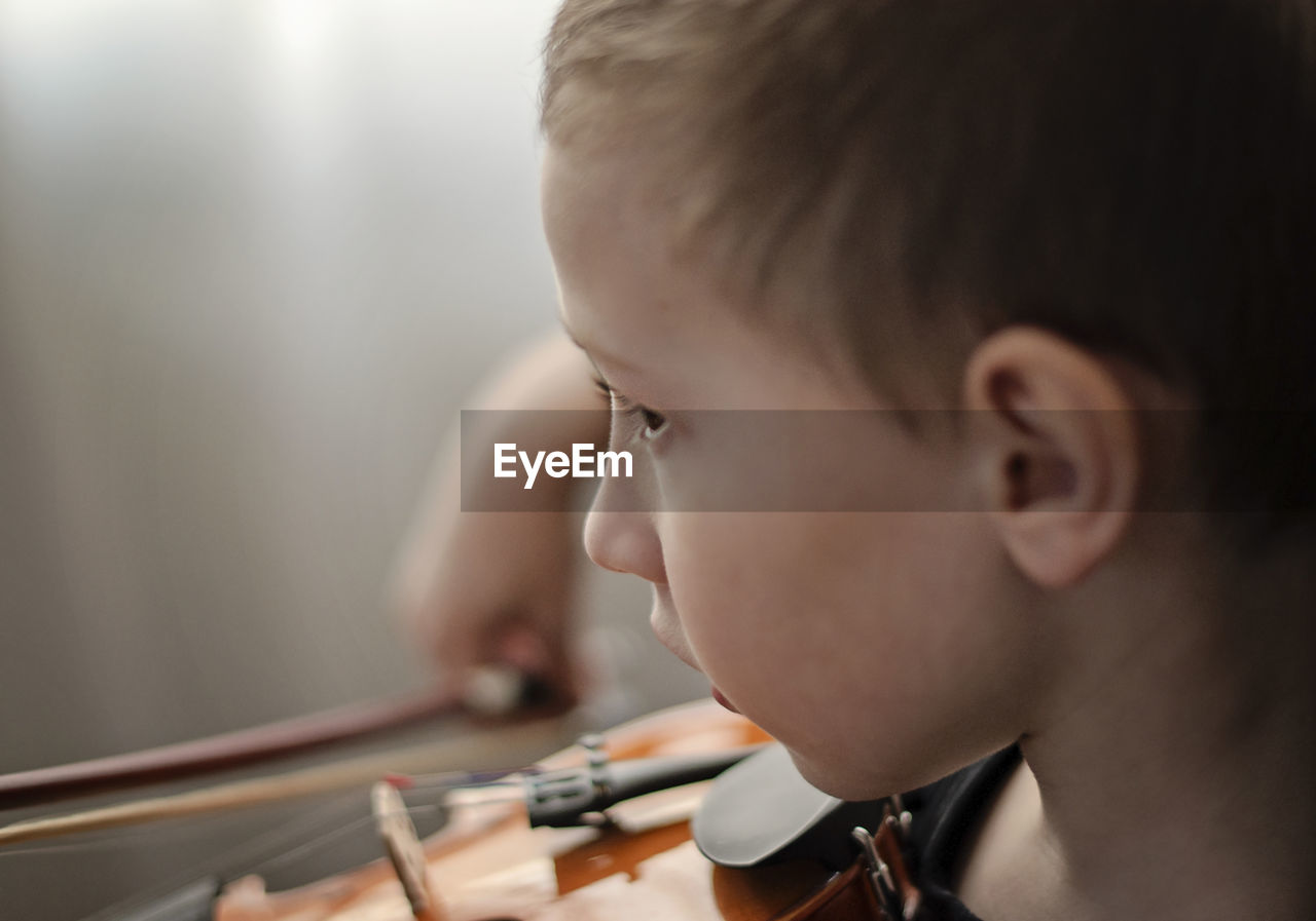 Close-up of boy playing violin at home