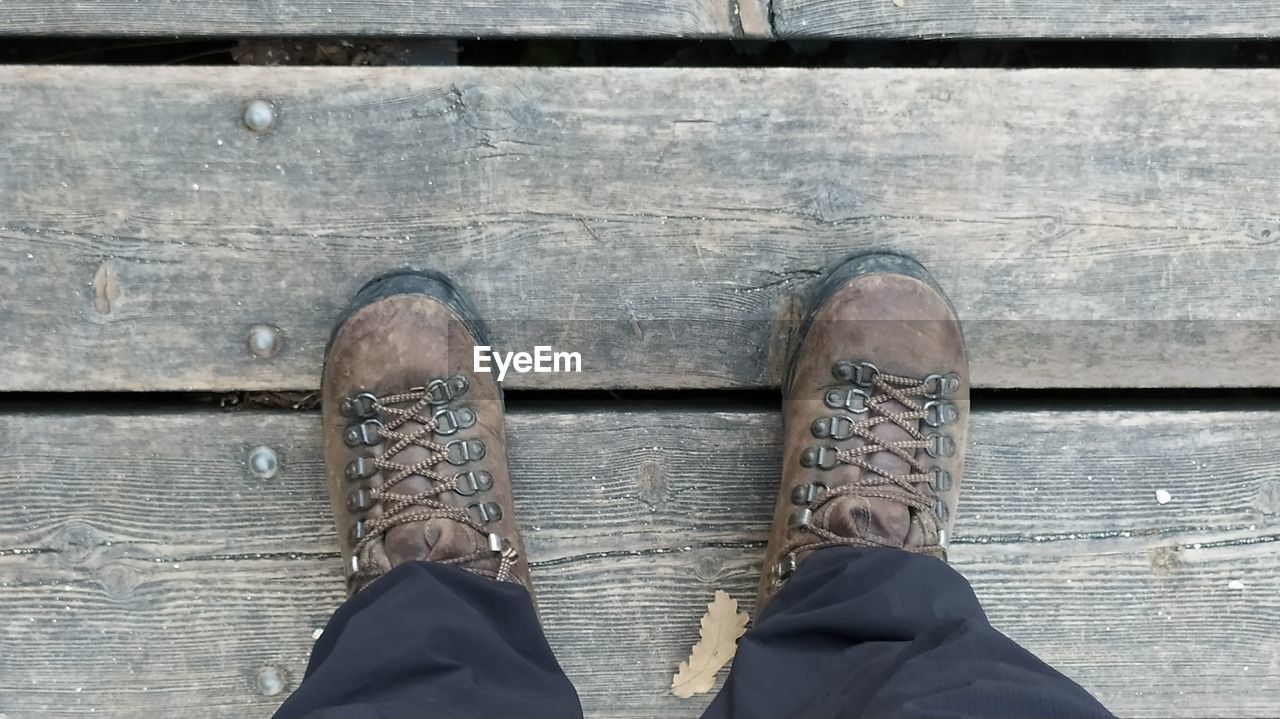 LOW SECTION OF MAN STANDING ON WOODEN FLOOR