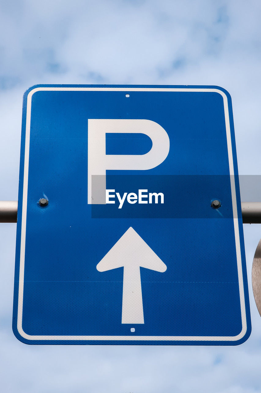 blue, sign, communication, guidance, road sign, symbol, road, traffic sign, arrow symbol, transportation, no people, directional sign, sky, street sign, traffic arrow sign, font, day, number, signage, cloud, close-up, disabled access, outdoors, white, mode of transportation, low angle view, vehicle registration plate