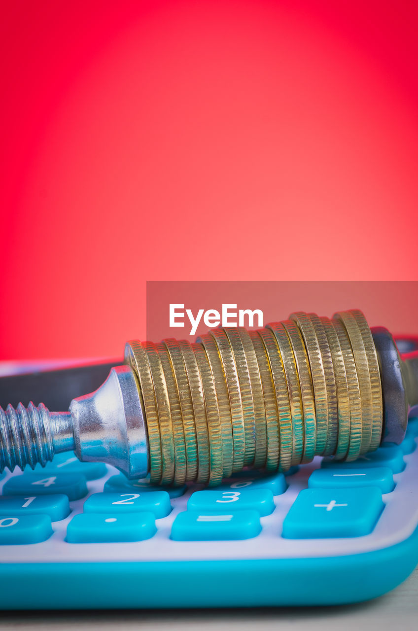 Close-up of coins over calculator against red background