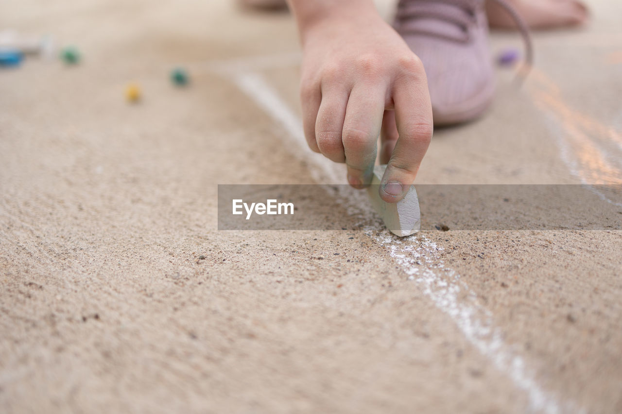 Girl draws with colorful crayons on pavement. children's drawings with chalk on wall. creative kid. 