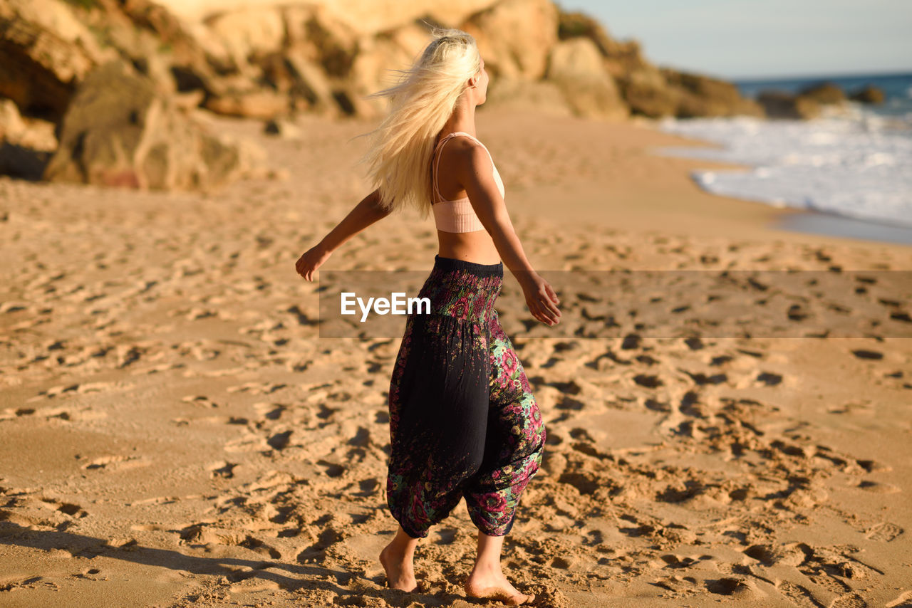 Young woman with arms outstretched standing at beach