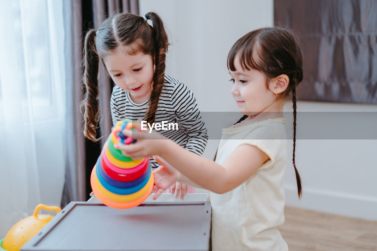 Sisters playing with multi colored toys at home