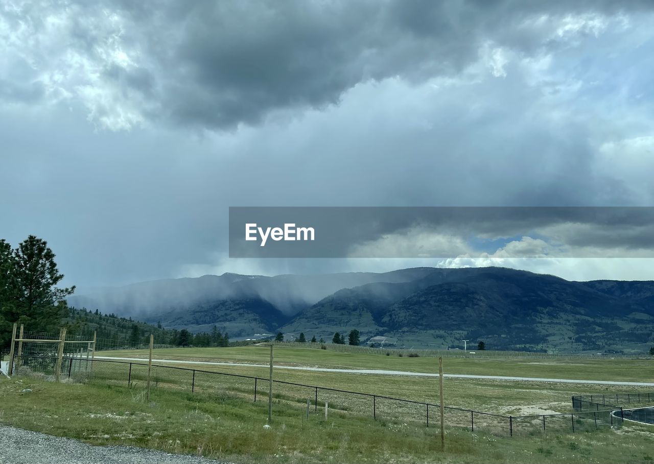 cloud, environment, landscape, sky, mountain, scenics - nature, beauty in nature, nature, land, fence, storm, plant, field, plain, no people, rural area, storm cloud, mountain range, dramatic sky, grass, rural scene, overcast, tree, outdoors, highland, grassland, cloudscape, tranquility, day, non-urban scene, rain, thunderstorm, fog, tranquil scene, wet, meadow, travel