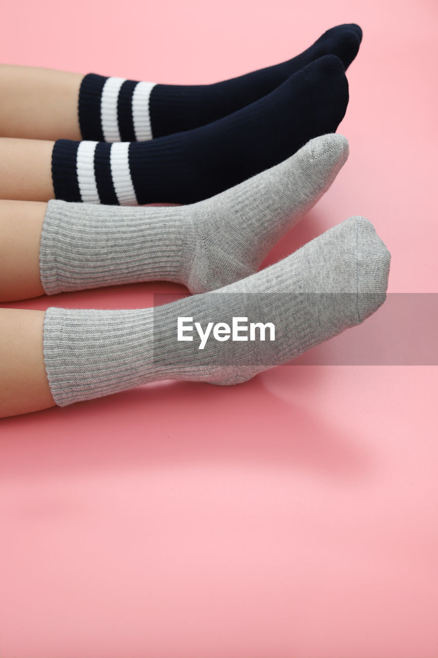 Low section of children wearing socks while resting over colored background