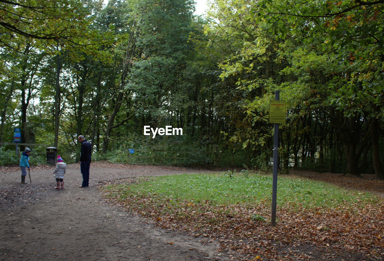 MEN WALKING ON ROAD AMIDST TREES