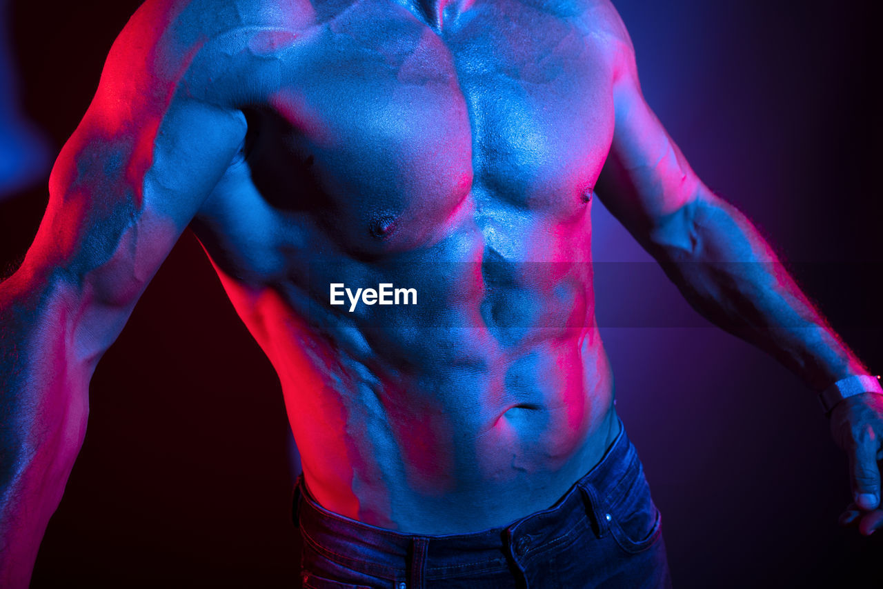 Close-up of shirtless man against black background